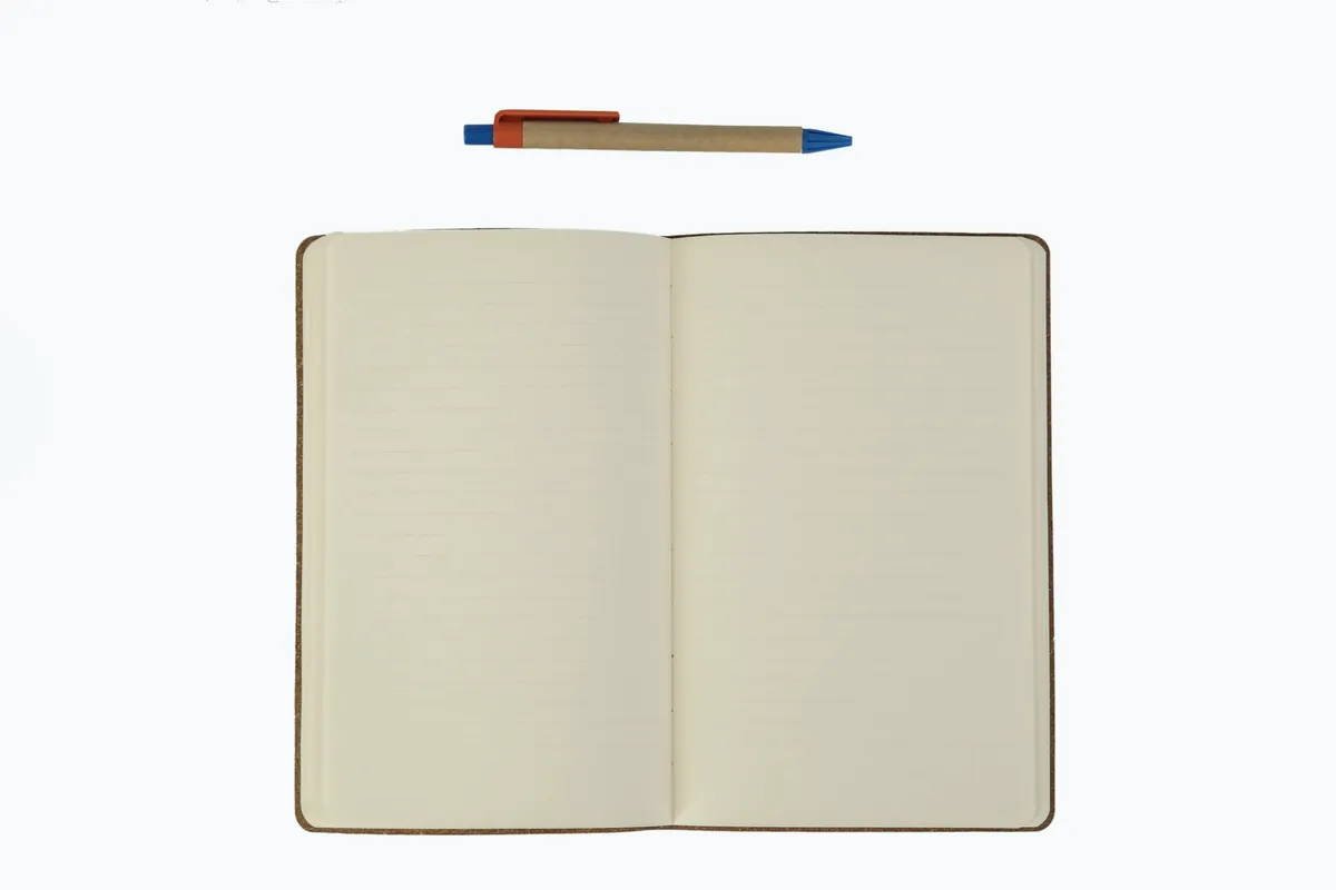 Un carnet ouvert et un stylo posés sur un fond clair